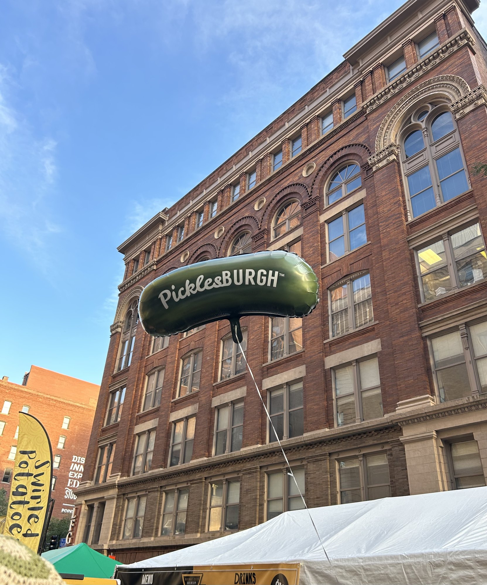 The Picklesburgh pickle balloon floating above a Pittsburgh street festival
